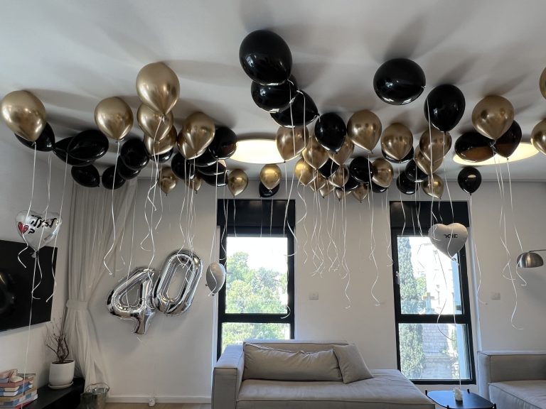 חדר יום הולדת 40 עם בלוני הליום בשחור וזהב וספרות כסופות